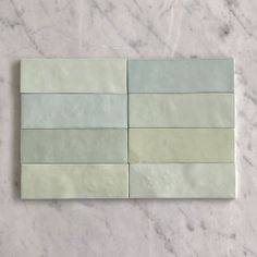 some white and green tiles on a marble counter top, with one tile in the middle