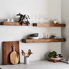 some shelves with wooden utensils and plates on them in a white kitchen area