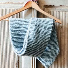 a blue knitted blanket hanging from a wooden hanger