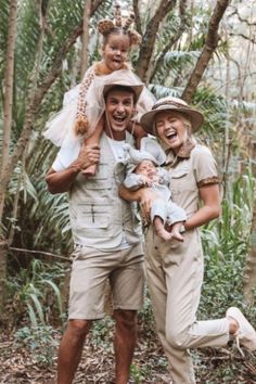 two men and a woman are standing in the woods with one holding a small child