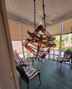 a stained glass chandelier hanging from the ceiling in a room with chairs and windows