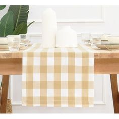 the table is set with plates, cups and napkins in front of a plant