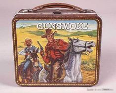 an old tin lunch box with the image of two cowboys on horses and gunsmoke