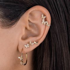 a close up of a woman's ear with two butterfly shaped earrings on it