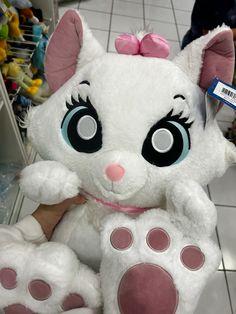 a large white stuffed animal with big blue eyes and pink ears sitting on the floor