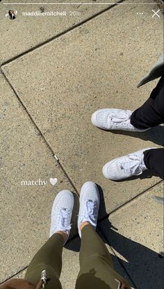 two people standing next to each other with their feet on the ground and one person wearing white sneakers