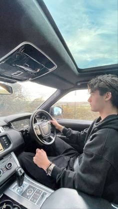 a man driving a car while wearing a black hoodie