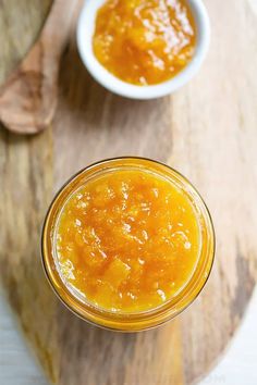 two small bowls filled with orange sauce on top of a wooden cutting board