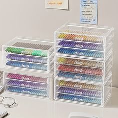 the drawers are filled with many different colored pens and pencils in clear plastic containers