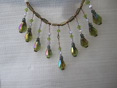 "Vintage charm with this sparkling addition to your collection,  a beautiful dark Peridot green color accented with genuine Swarovski crystals    Dangle length is approx 2 1/2\" Length approx 16\" fastens securely with a magnetic clasp  Matching earrings available for an additional $11" Green Czech Glass Necklace With Dangling Beads, Green Necklaces With Dangling Beads, Green Dangle Necklace With Beads, Green Dangle Jewelry With Bead Caps, Green Crystal Beaded Necklace For Gift, Green Crystal Beaded Necklaces As Gift, Green Faceted Bead Dangle Necklace, Green Dangle Necklace With Faceted Beads, Beaded Crystal Dangle Necklaces