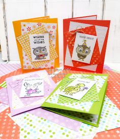 four cards with owls on them sitting on top of a colorful cloth covered tablecloth