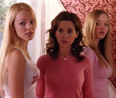 three women standing in front of a red wall