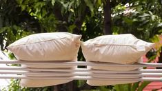 two pillows are sitting on the back of a metal rail in front of some trees