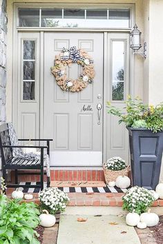 a front porch with two chairs and a wreath on the door, surrounded by potted plants