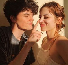 a young man and woman are looking at each other's eyes with their fingers together