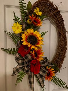 a wreath with sunflowers and other flowers is hanging on the front door,