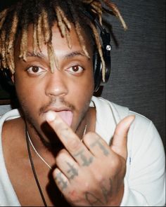 a young man with dreadlocks making a hand gesture while wearing headphones and listening to music