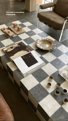 a checkered table with plates and cups on it in front of a brown leather chair