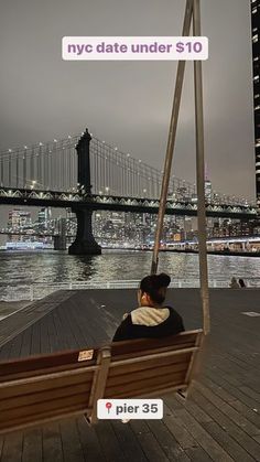 a man and woman sitting on a swing in front of the water