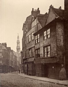 an old black and white photo of buildings on a cobblestone street