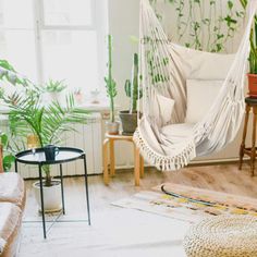 a hammock hanging in a living room with potted plants on the wall