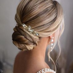 a woman with blonde hair in a low updo wearing a gold headpiece and earrings