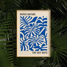 a blue and white poster hanging from the side of a palm leaf covered wall with text paper nature the cut - outs