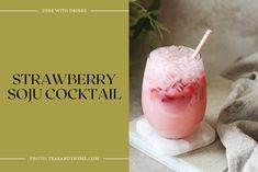 a drink with strawberries in it sitting on top of a book next to a plant