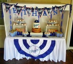 a table topped with cakes and cupcakes under a banner