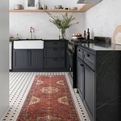 a kitchen with black cabinets and an area rug