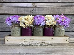 four mason jars with purple and yellow flowers in them