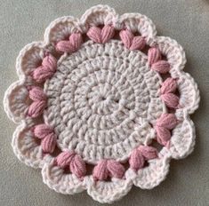 a crocheted doily with pink and white flowers