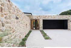 a stone house with two garages on each side and one door open to the outside