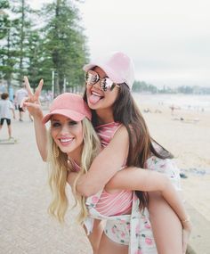 two young women on the beach one is holding her arm around the other's shoulder