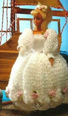 a doll is dressed in a white crochet dress