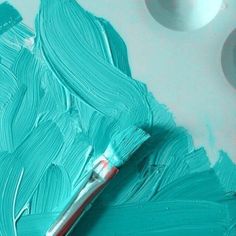 a paintbrush is sitting on top of some blue paints