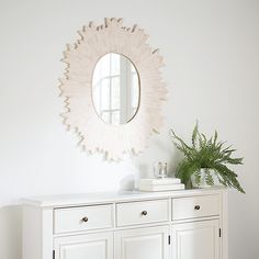 a white dresser with a mirror above it and a potted plant sitting on top