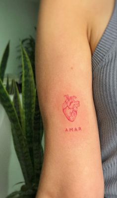 a woman's arm with a small heart tattoo on the left side of her arm