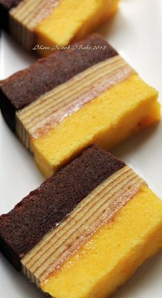 three pieces of cake sitting on top of a white plate covered in chocolate and yellow icing