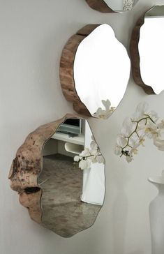 three mirrors mounted to the side of a wall next to a vase with flowers on it