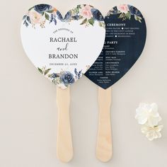 two wooden paddles with floral designs on them and the names of their wedding guests