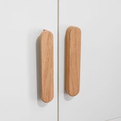 two wooden door handles on a white cabinet