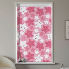 a window with pink and white stars on the blind in front of a gray wall