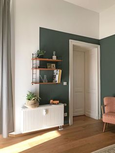 a living room with green walls and shelves on the wall, there is a radiator