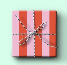 a pink and red striped gift box tied up with twine on mint green background