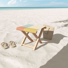 a wooden table sitting on top of a beach next to a pair of flip flops