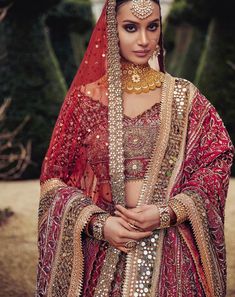 a woman wearing a red and gold bridal outfit