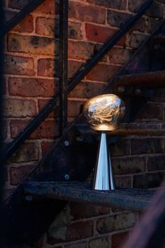 a close up of a metal object on a brick wall next to a stair case