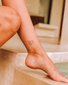 a woman's foot with a small tattoo on her left leg, sitting in a bathtub