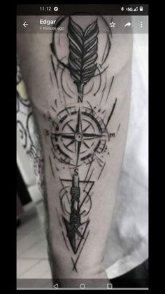 a man's arm with an arrow and compass tattoo on it